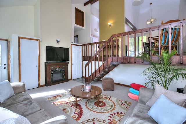 living room featuring a glass covered fireplace, high vaulted ceiling, carpet, and stairs