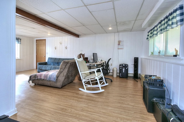 living room with a drop ceiling, plenty of natural light, and light wood-style flooring