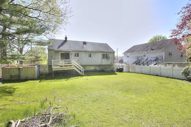 rear view of property with a deck, a fenced backyard, a chimney, a yard, and stairway