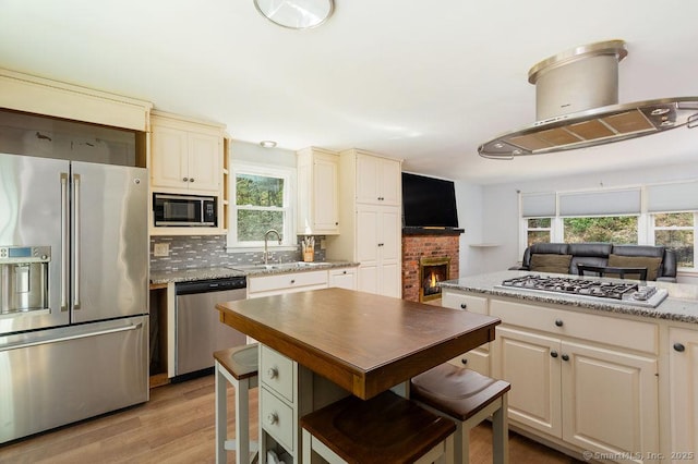 38 Black Bridge Rd, Newtown, CT 06482 - kitchen featuring a sink, stainless steel appliances, decorative backsplash, cream cabinetry, and light wood-type flooring