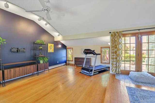 workout area featuring wood finished floors, rail lighting, ceiling fan, vaulted ceiling, and a baseboard radiator