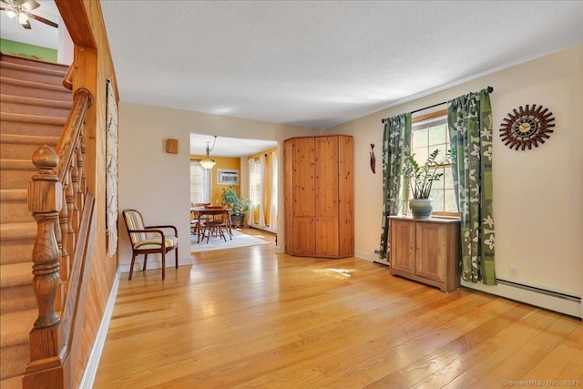 interior space featuring stairway, a textured ceiling, a wealth of natural light, and light wood-type flooring