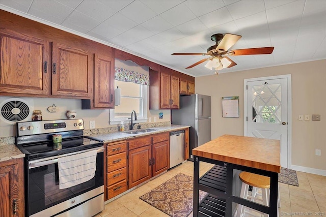 kitchen featuring a sink, brown cabinetry, ceiling fan, light tile patterned floors, and appliances with stainless steel finishes