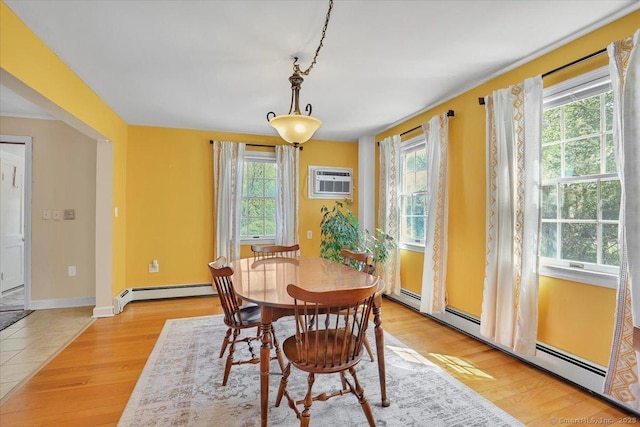 dining area with baseboards, baseboard heating, light wood-style flooring, and a wall unit AC