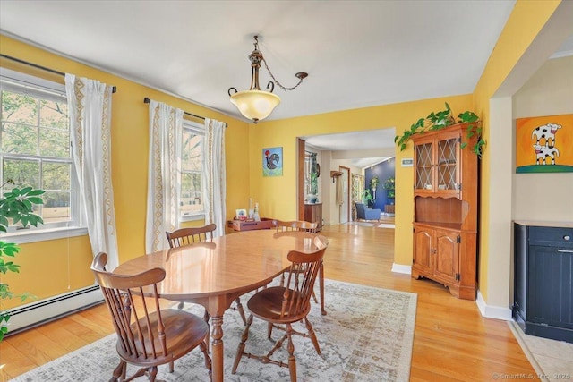 dining room featuring baseboards, a baseboard radiator, and light wood-style flooring