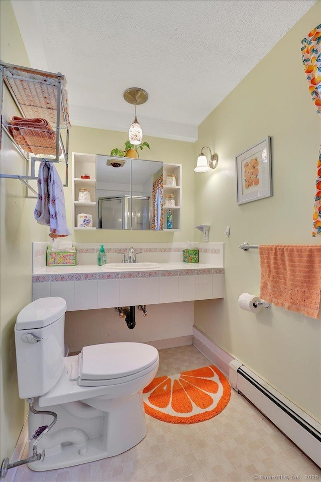 full bath featuring toilet, a sink, a shower with door, a textured ceiling, and a baseboard radiator