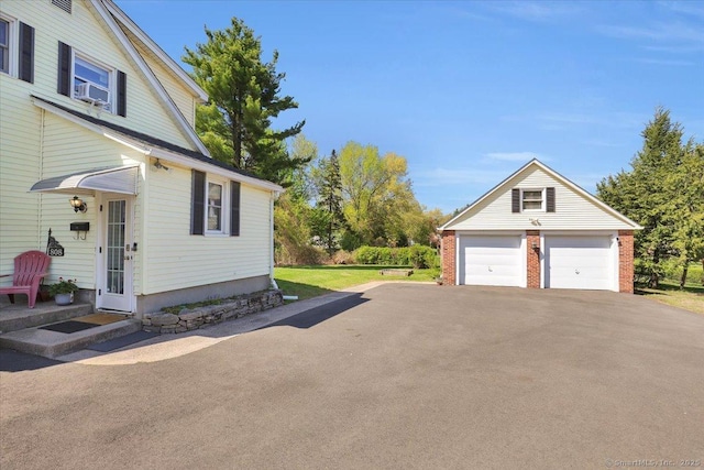 view of side of home with a detached garage, an outbuilding, and brick siding