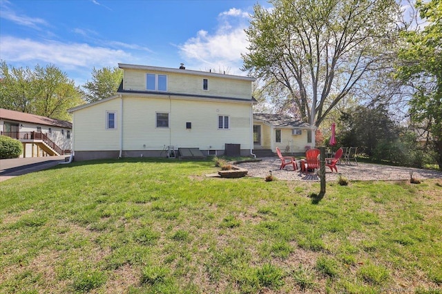 rear view of property featuring an outdoor fire pit and a lawn