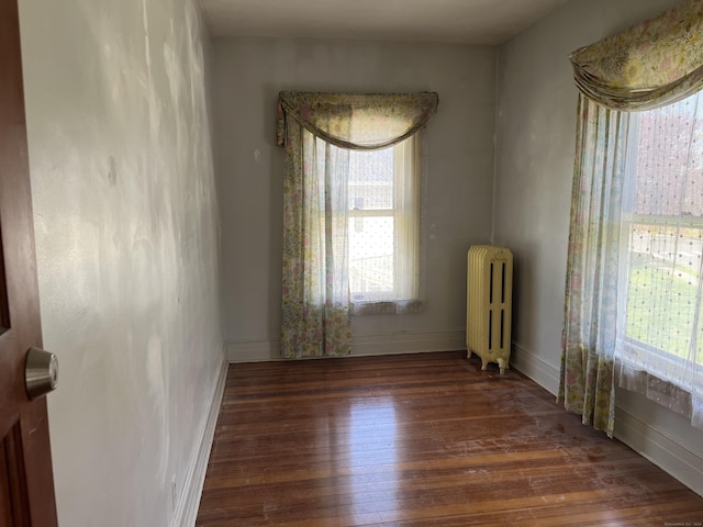 unfurnished room with wood finished floors, baseboards, and radiator heating unit
