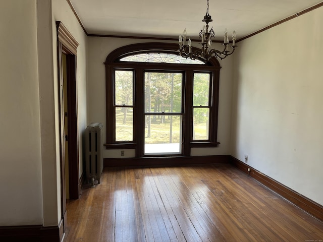 interior space with a notable chandelier, a healthy amount of sunlight, radiator heating unit, and hardwood / wood-style flooring
