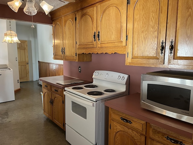 kitchen featuring a notable chandelier, white range with electric cooktop, dark floors, stainless steel microwave, and washer / dryer