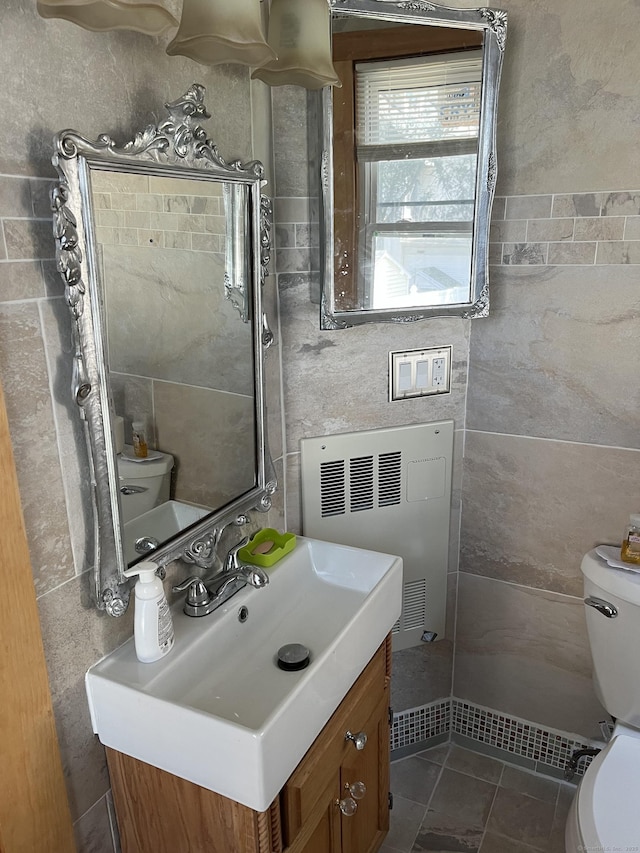 half bathroom with toilet, tile patterned floors, radiator, and vanity
