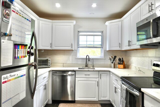 kitchen with appliances with stainless steel finishes, a sink, white cabinetry, backsplash, and recessed lighting