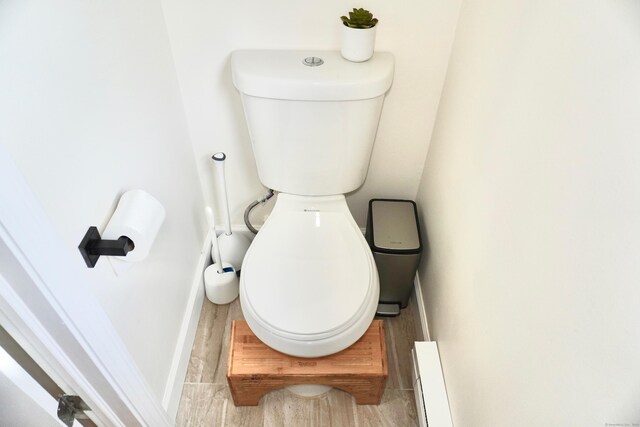 bathroom with toilet, baseboards, and wood finished floors