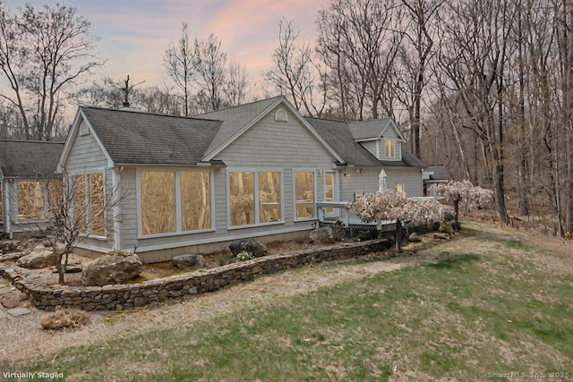 rear view of property with a lawn and roof with shingles