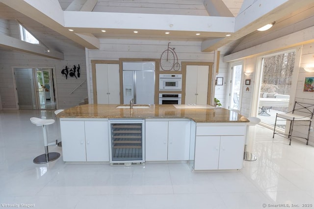kitchen with beverage cooler, paneled built in refrigerator, recessed lighting, white cabinetry, and oven
