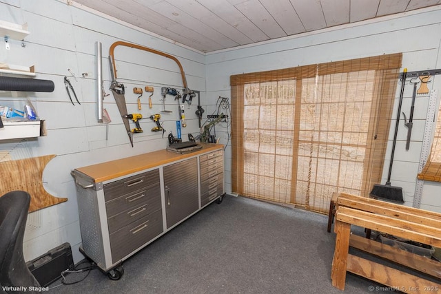 misc room featuring wooden ceiling, dark colored carpet, and a workshop area
