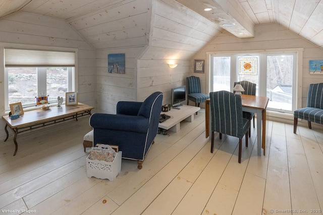 interior space featuring light wood-style floors, a wealth of natural light, wood walls, and lofted ceiling