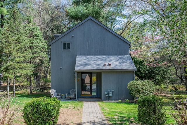 rear view of house featuring a lawn and a shingled roof