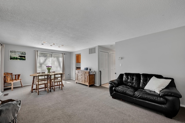living area with baseboards, light colored carpet, a textured ceiling, and visible vents