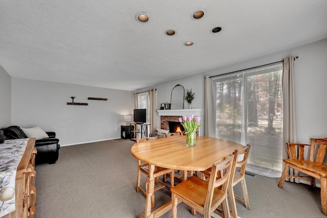 dining room with baseboards, carpet flooring, a textured ceiling, and a brick fireplace