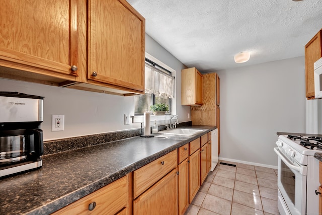 kitchen with light tile patterned flooring, dark countertops, white appliances, a textured ceiling, and a sink