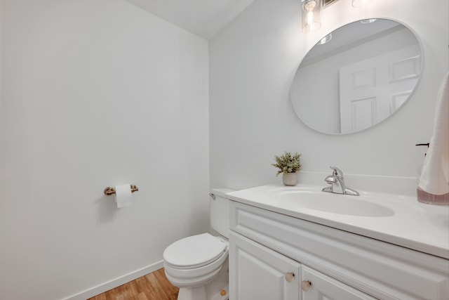 bathroom featuring toilet, baseboards, wood finished floors, and vanity