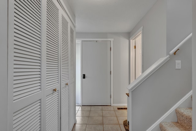 hall with light tile patterned floors, baseboards, stairs, and visible vents