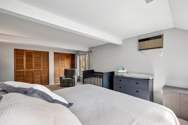carpeted bedroom featuring a wall mounted AC and lofted ceiling