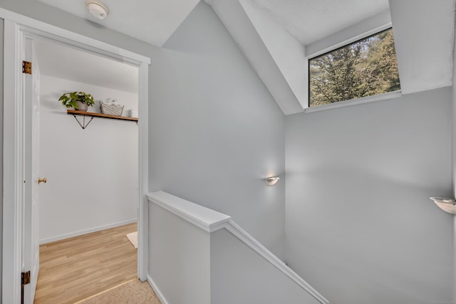 hall with baseboards, wood finished floors, and an upstairs landing
