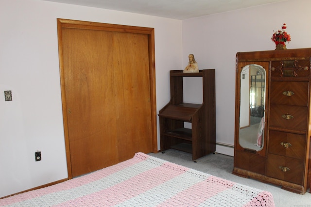 carpeted bedroom with a baseboard heating unit and a closet