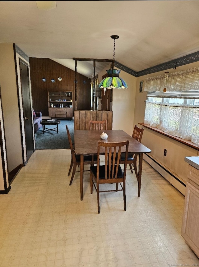 dining area with wooden walls, light floors, a baseboard radiator, and lofted ceiling