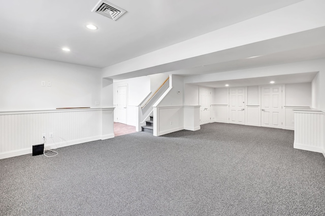 finished basement featuring recessed lighting, stairway, dark colored carpet, and visible vents