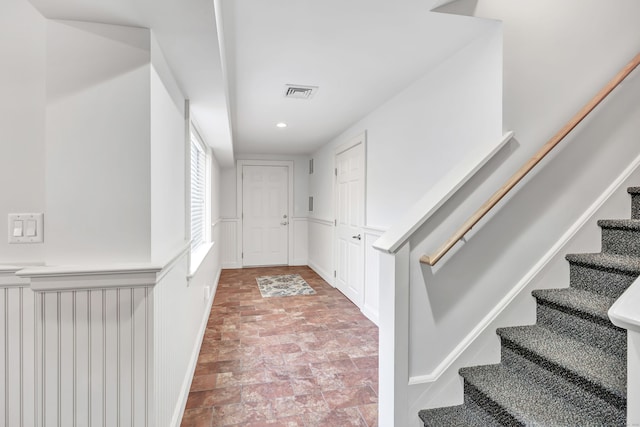 interior space featuring visible vents, stone finish flooring, and wainscoting