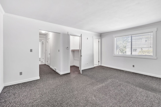 interior space with crown molding, baseboards, visible vents, and dark colored carpet