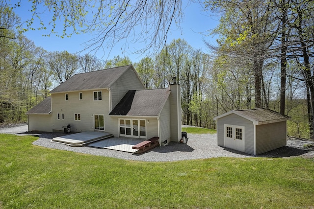 rear view of property with an outdoor structure, a deck, french doors, a chimney, and a yard