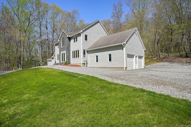 exterior space with a lawn, gravel driveway, a shingled roof, and a garage