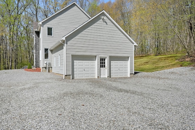 view of side of home with an attached garage and gravel driveway