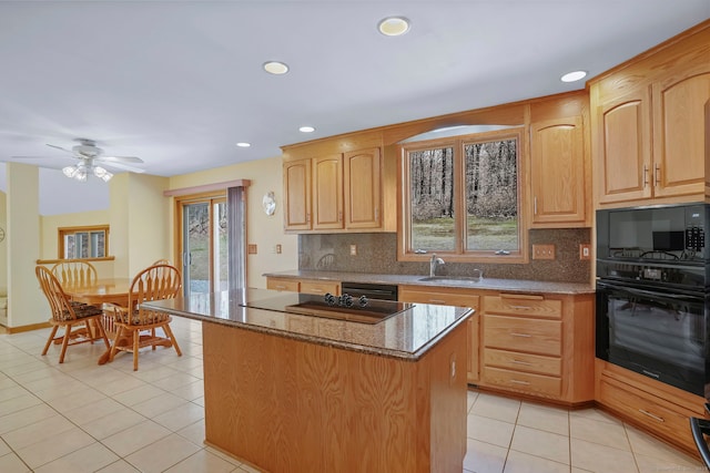kitchen with dark stone counters, a kitchen island, a wealth of natural light, and black appliances