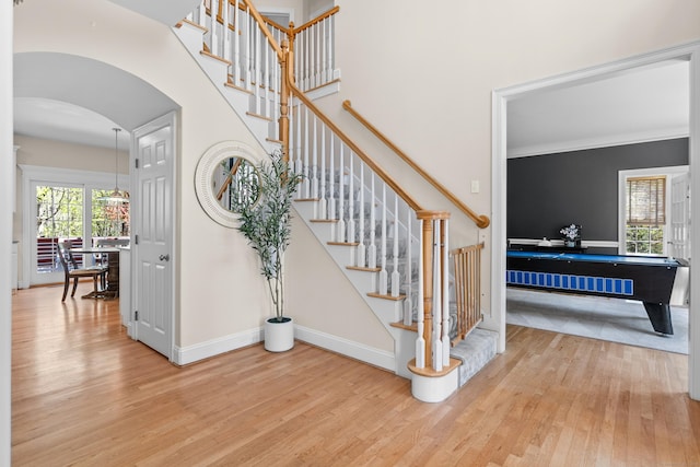 stairway featuring baseboards, arched walkways, and wood finished floors