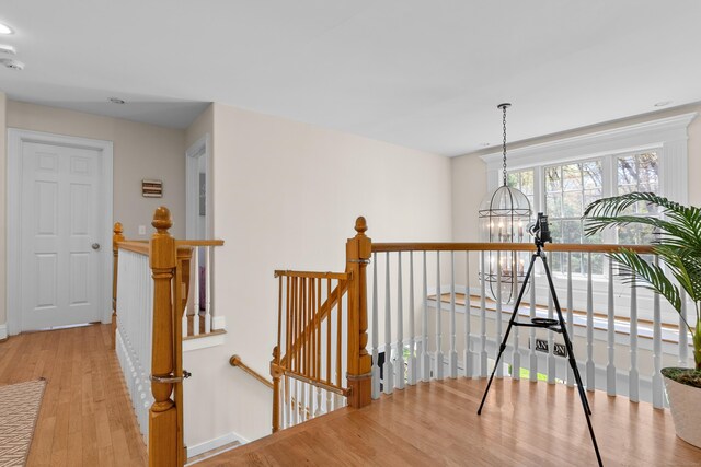 corridor featuring an inviting chandelier, recessed lighting, baseboards, an upstairs landing, and wood finished floors