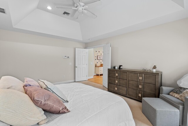 bedroom with light colored carpet, a raised ceiling, recessed lighting, a ceiling fan, and visible vents