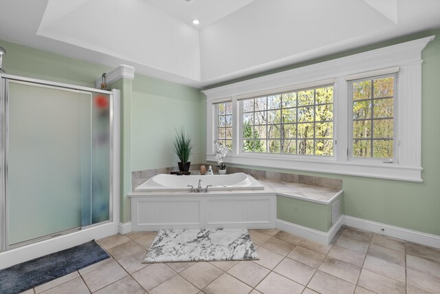 full bathroom featuring a raised ceiling, tile patterned floors, a garden tub, and a stall shower