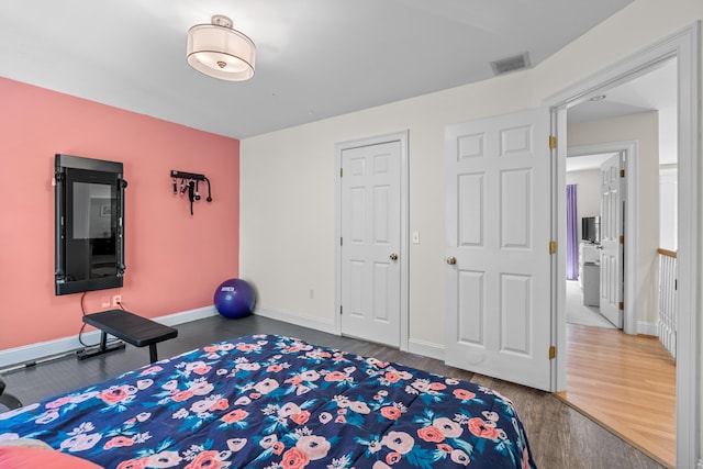 bedroom with baseboards, visible vents, and wood finished floors