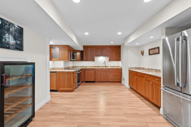 kitchen with beverage cooler, recessed lighting, light wood-type flooring, a sink, and appliances with stainless steel finishes