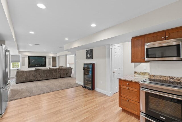 kitchen with appliances with stainless steel finishes, brown cabinets, light wood finished floors, beverage cooler, and recessed lighting