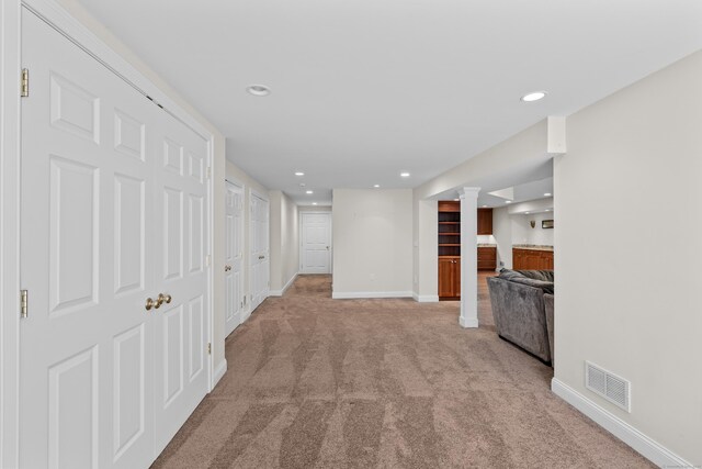corridor featuring baseboards, light colored carpet, recessed lighting, and visible vents