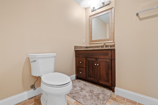 half bath with toilet, baseboards, and vanity
