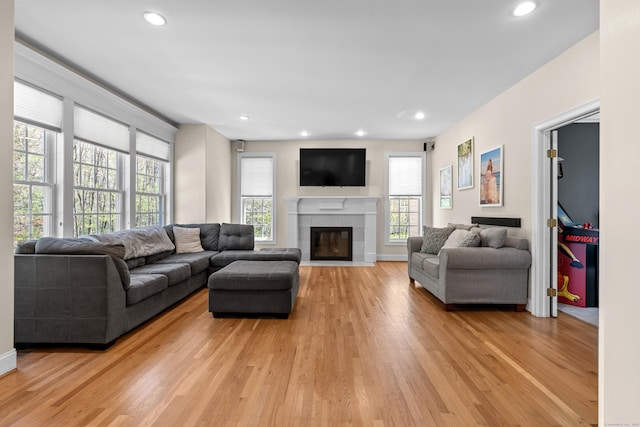 living area featuring recessed lighting, baseboards, a fireplace, and light wood finished floors