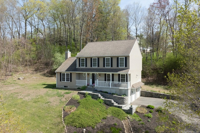 view of front facade featuring an attached garage, a front yard, a chimney, covered porch, and driveway
